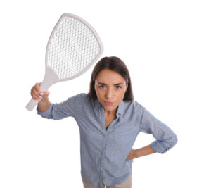 Young woman with electric fly swatter on white background. Insect killer guy spraying deck with water. needs pest control instead.